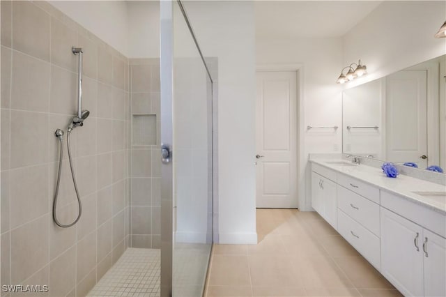 bathroom with tile patterned flooring, vanity, and tiled shower