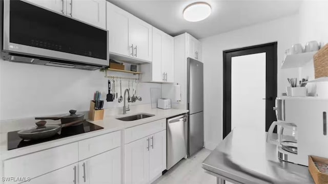 kitchen with white cabinets, appliances with stainless steel finishes, light countertops, open shelves, and a sink