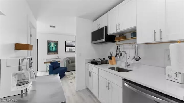 kitchen featuring a sink, white cabinetry, light countertops, appliances with stainless steel finishes, and open shelves