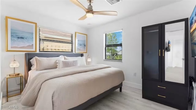 bedroom featuring a ceiling fan, light wood-type flooring, visible vents, and baseboards