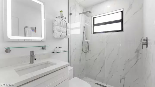 bathroom featuring toilet, a marble finish shower, and vanity