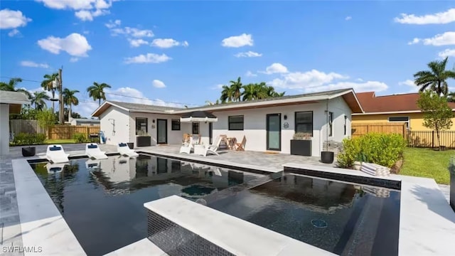 rear view of property featuring a patio area, a pool with connected hot tub, and fence