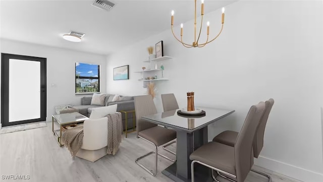 dining area featuring a chandelier, visible vents, light wood-style flooring, and baseboards