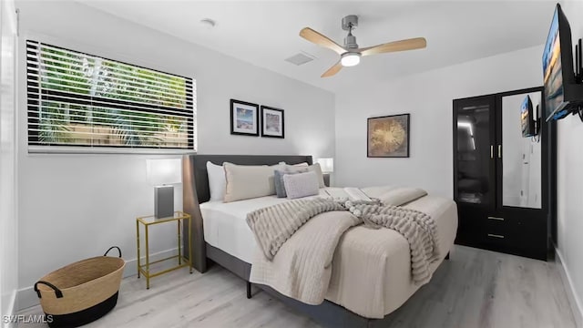 bedroom with a ceiling fan, visible vents, and wood finished floors