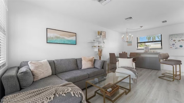 living area with light wood finished floors, visible vents, and a chandelier