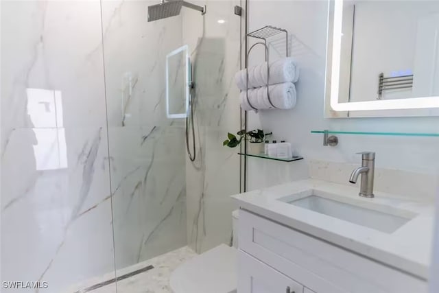 full bath featuring a marble finish shower and vanity