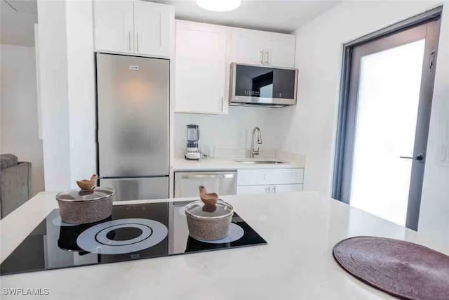 kitchen with stainless steel appliances, plenty of natural light, white cabinetry, and a sink