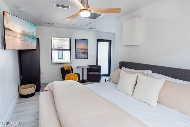 bedroom featuring visible vents, light wood-style flooring, attic access, a ceiling fan, and baseboards