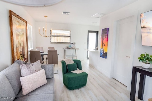 living room with light wood-type flooring, visible vents, and an inviting chandelier