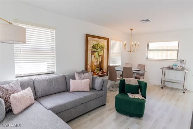 living area with wood finished floors, visible vents, and a notable chandelier