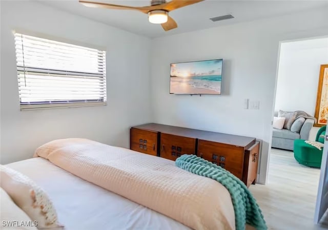 bedroom featuring a ceiling fan, visible vents, and wood finished floors