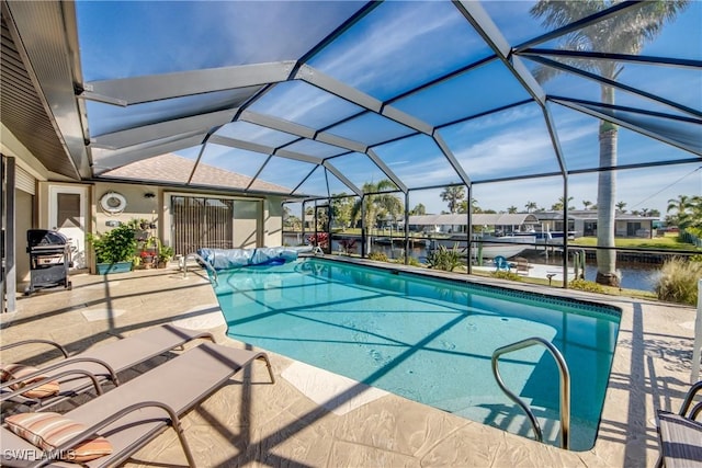 view of pool featuring grilling area, a water view, glass enclosure, and a patio area