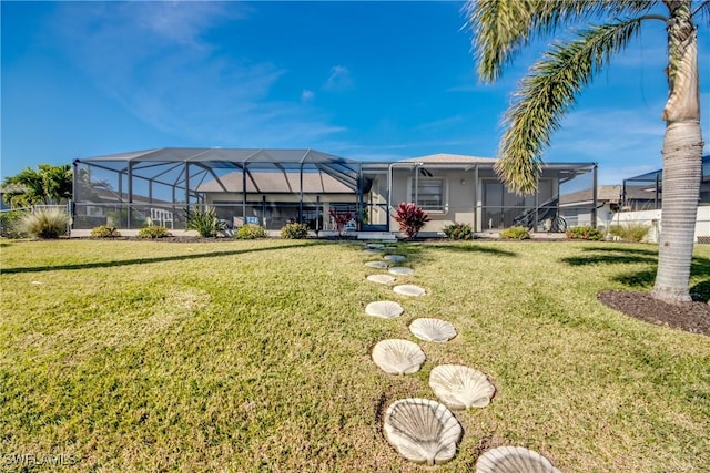 rear view of house featuring a yard and glass enclosure