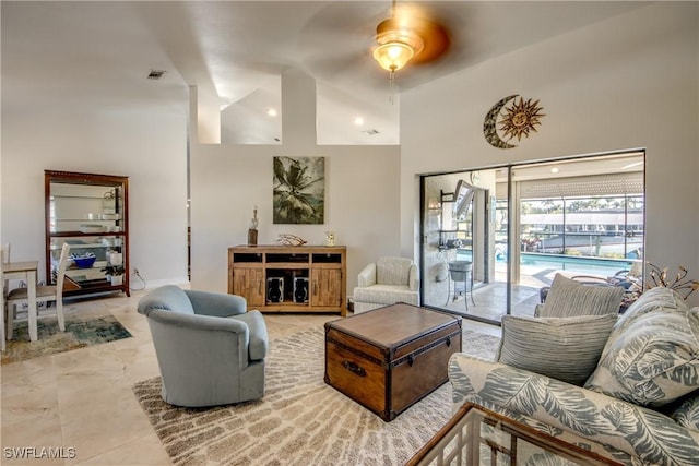 living room with a towering ceiling, light tile patterned floors, and ceiling fan