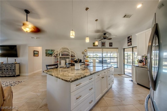 kitchen with pendant lighting, stainless steel fridge, white cabinetry, light stone counters, and a kitchen island