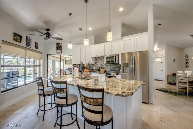 kitchen featuring tasteful backsplash, appliances with stainless steel finishes, decorative light fixtures, and white cabinets