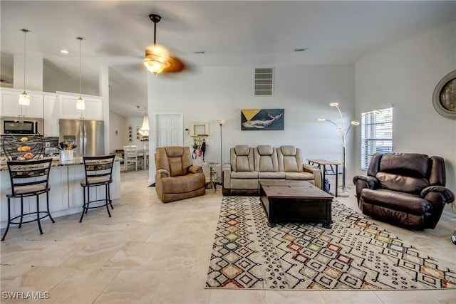 living room with ceiling fan and a towering ceiling