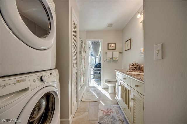 laundry area with stacked washer and dryer and sink