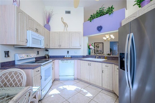 kitchen with sink, a high ceiling, light tile patterned floors, white appliances, and an inviting chandelier