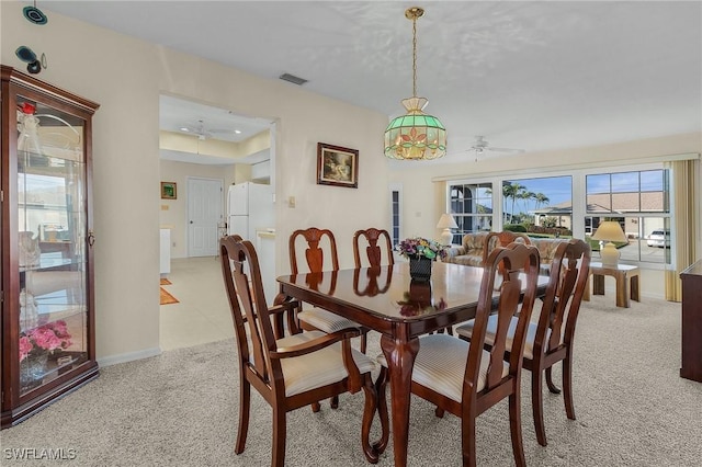 carpeted dining room with ceiling fan