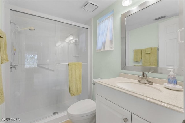 bathroom featuring vanity, a shower with shower door, and toilet