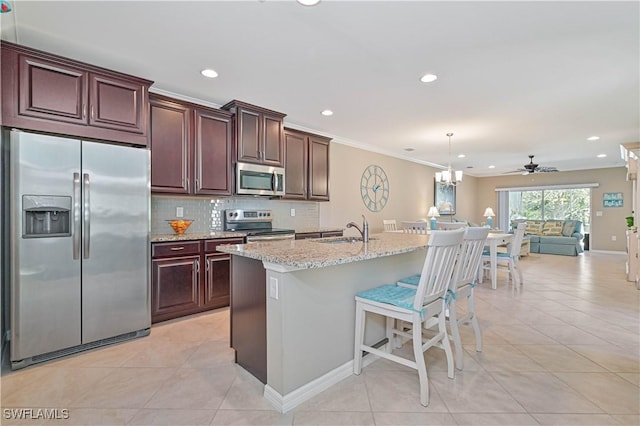 kitchen with hanging light fixtures, appliances with stainless steel finishes, sink, and a kitchen island with sink