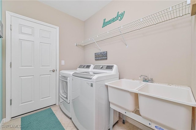 clothes washing area with washer and dryer, sink, and light tile patterned floors