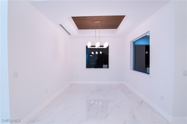 empty room featuring an inviting chandelier and a tray ceiling