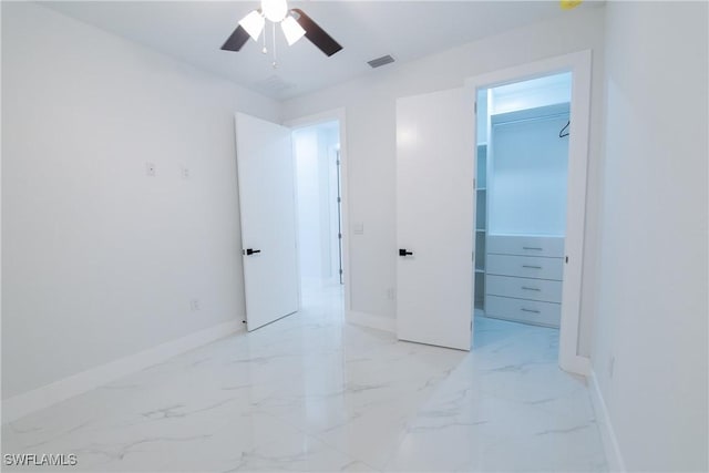 unfurnished bedroom featuring a walk in closet, ceiling fan, and a closet