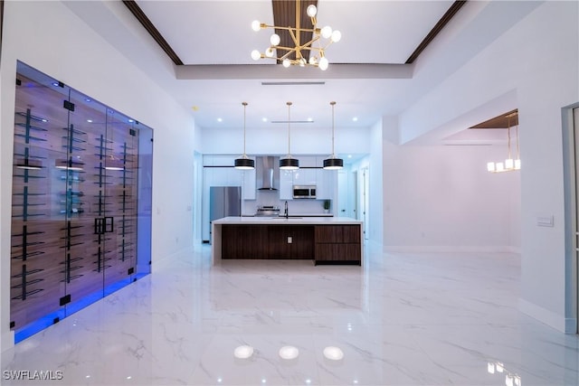 kitchen featuring sink, decorative light fixtures, a chandelier, a large island, and wall chimney range hood