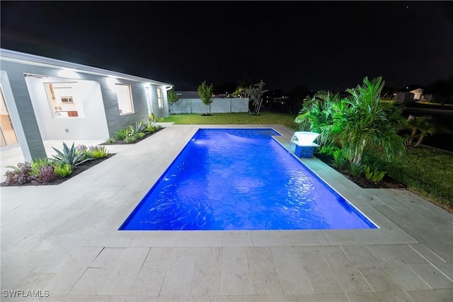 pool at night featuring a patio