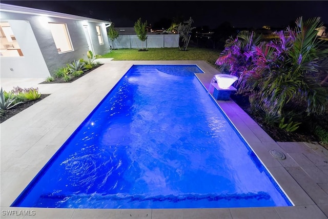 pool at night with a patio area