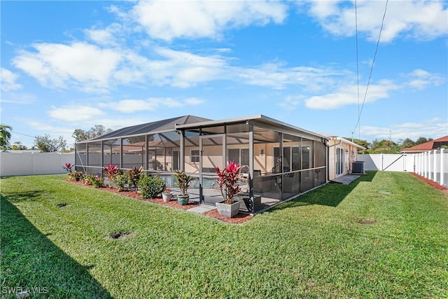 rear view of house with a pool, a yard, a lanai, and central air condition unit