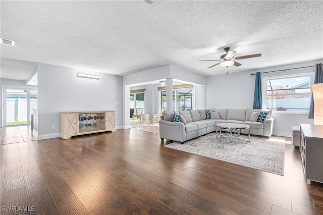 living room featuring a healthy amount of sunlight, dark hardwood / wood-style floors, a textured ceiling, and ceiling fan