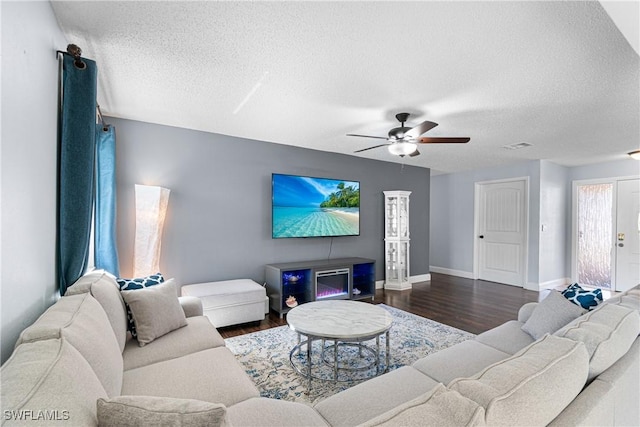 living room featuring ceiling fan, dark hardwood / wood-style floors, and a textured ceiling