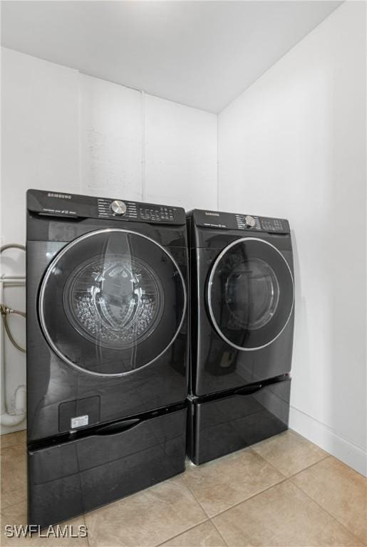 clothes washing area with light tile patterned flooring and washing machine and dryer