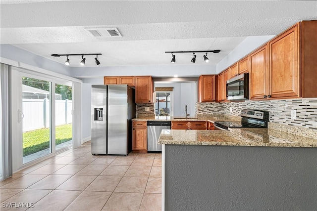 kitchen featuring sink, light tile patterned floors, appliances with stainless steel finishes, light stone countertops, and kitchen peninsula