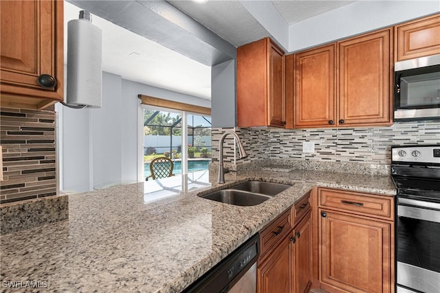 kitchen featuring stainless steel appliances, light stone countertops, sink, and backsplash