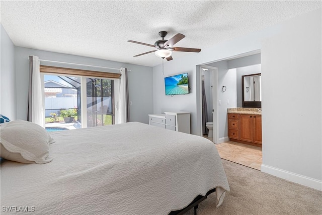 bedroom with ensuite bath, light colored carpet, access to exterior, ceiling fan, and a textured ceiling