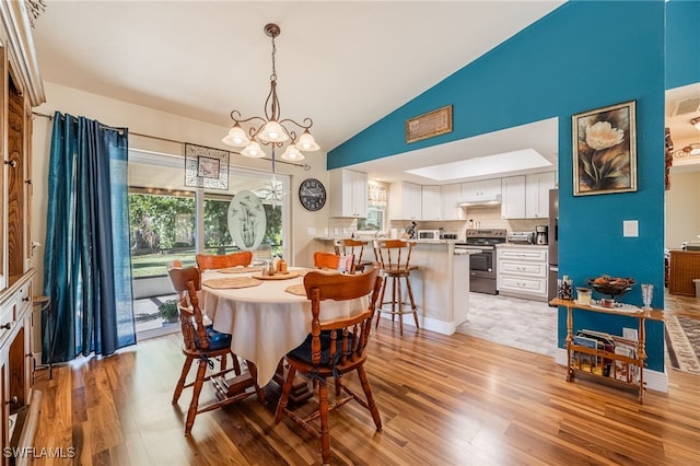 dining area featuring light hardwood / wood-style flooring, high vaulted ceiling, and a chandelier