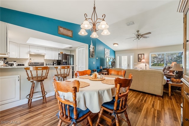 dining room featuring hardwood / wood-style flooring, ceiling fan with notable chandelier, and french doors