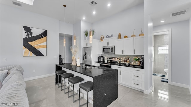 kitchen featuring sink, a breakfast bar, stainless steel appliances, white cabinets, and decorative backsplash