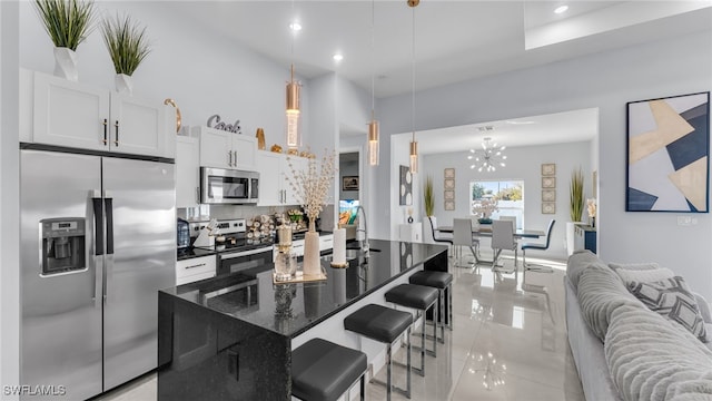 kitchen with pendant lighting, white cabinetry, dark stone countertops, a center island, and stainless steel appliances