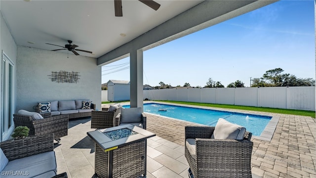 view of pool with an outdoor living space with a fire pit, a patio, ceiling fan, and a storage unit