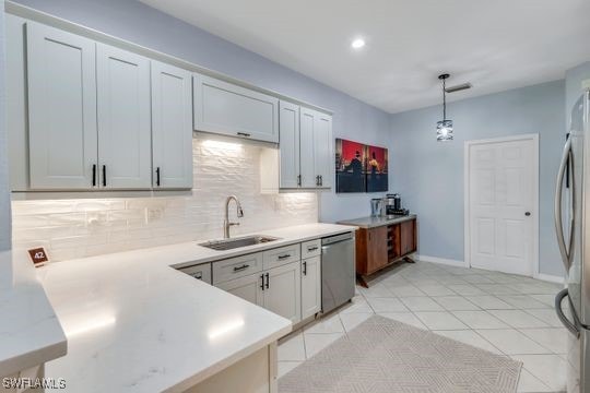 kitchen featuring light tile patterned flooring, decorative light fixtures, sink, backsplash, and stainless steel appliances