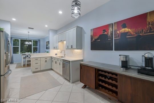 kitchen featuring light tile patterned flooring, sink, hanging light fixtures, kitchen peninsula, and stainless steel appliances