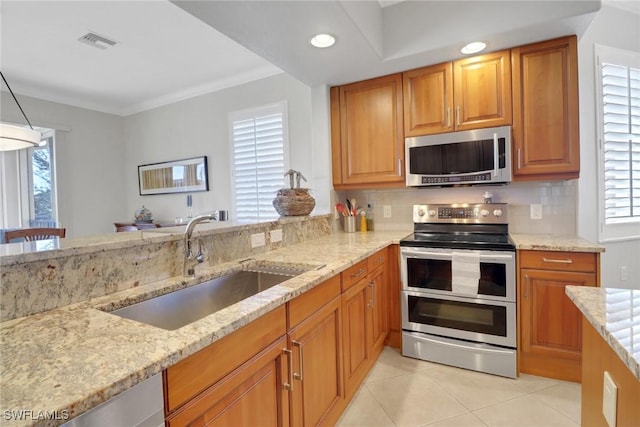 kitchen featuring light stone counters, stainless steel appliances, sink, and decorative backsplash