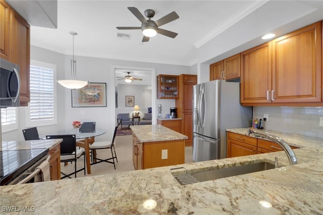 kitchen featuring sink, light stone counters, a kitchen island, pendant lighting, and stainless steel appliances