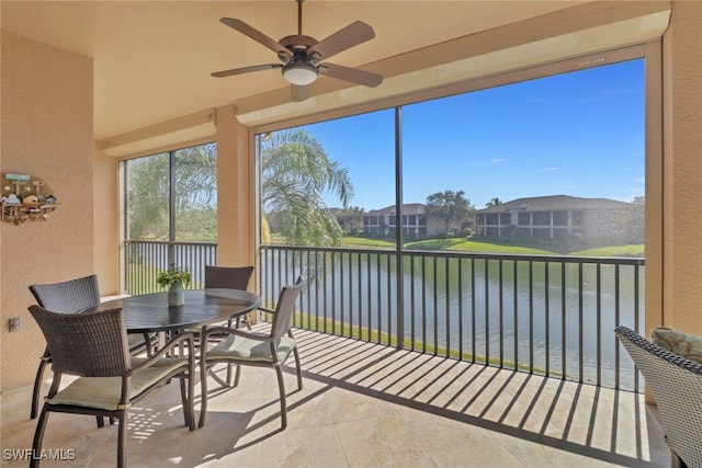 sunroom with a water view and ceiling fan