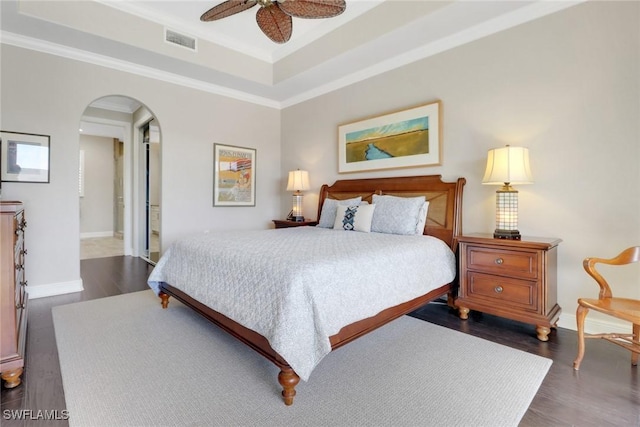 bedroom featuring a raised ceiling, ornamental molding, dark hardwood / wood-style floors, and ceiling fan